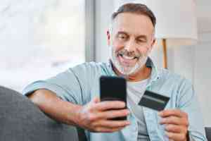 © K Davis/peopleimages.com - stock.adobe.com Mann mit Smartphone und Kredikarte