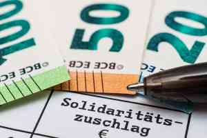 © Stockfotos-MG - stock.adobe.com Schriftzug Solidaritätszuschlag und Geldscheine